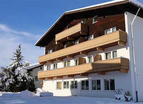 A modern building in winter, surrounded by snow. The blue sky and the snow-covered trees give the scene a tranquil atmosphere.