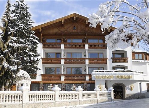 A charming hotel in the winter snow. The facade is traditionally designed, surrounded by snow-covered trees.