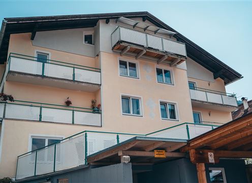 A modern building with several balconies and large windows. The facade is in light colors and has a simple, inviting style.