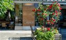 Un restaurant élégant avec l'inscription "Bogner". Devant l'entrée, des roses rouges fleurissent et il y a quelques tables en plein air.