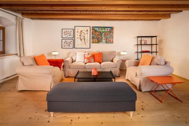 Ein gemütliches Wohnzimmer mit hellen Sofas und bunten Kissen. Es gibt einen eleganten Couchtisch und dekorative Kunst an der Wand.