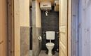 Ein modernes Badezimmer mit einem Toilettenraum und eleganten Fliesen. Die Wände sind teilweise aus Holz und die Beleuchtung sorgt für eine einladende Atmosphäre.