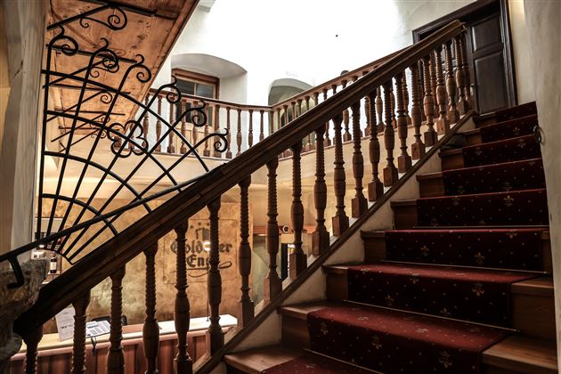 Un bel escalier avec rampe en bois et tapis rouge. Les murs sont clairs et donnent une atmosphère accueillante à la pièce.