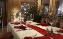 A festively laid table with red napkins and glasses. In the background stands a decorated Christmas tree.