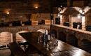 A cozy wine cellar with brick walls and soft lighting. A large wooden table with glasses and bottles created an inviting atmosphere.