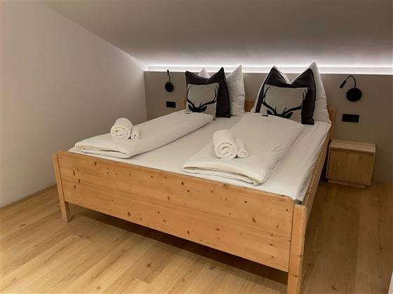 Une chambre moderne avec un lit en bois et de grands coussins. Des serviettes propres sont soigneusement disposées sur les lits.
