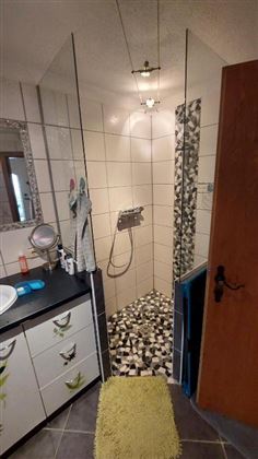 Ein modernes Badezimmer mit einer Dusche aus Glas ist zu sehen. Der Boden ist mit einem stilvollen Mosaikmuster gestaltet.