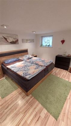 Ein gemütliches Schlafzimmer mit einem Doppelbett und bunten Bettwäsche. Der Raum hat eine helle Atmosphäre und einen Holzfußboden.