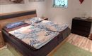 Ein gemütliches Schlafzimmer mit einem Doppelbett und bunten Bettwäsche. Der Raum hat eine helle Atmosphäre und einen Holzfußboden.
